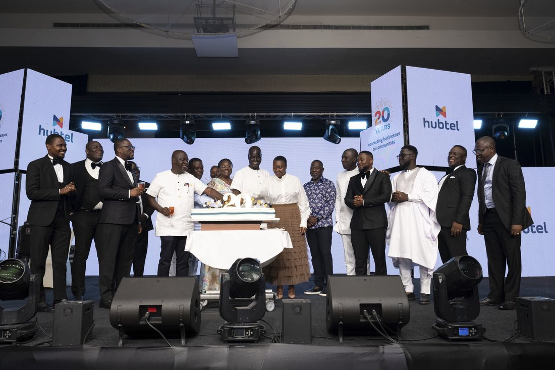 The full leadership group on stage around the 20th anniversary cake